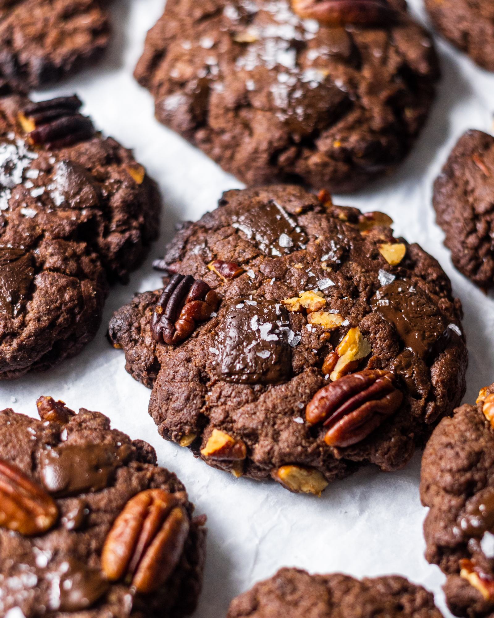 Vegan double Chocolate chip Cookies with pecans. photographed from above, arranged on white baking parchment