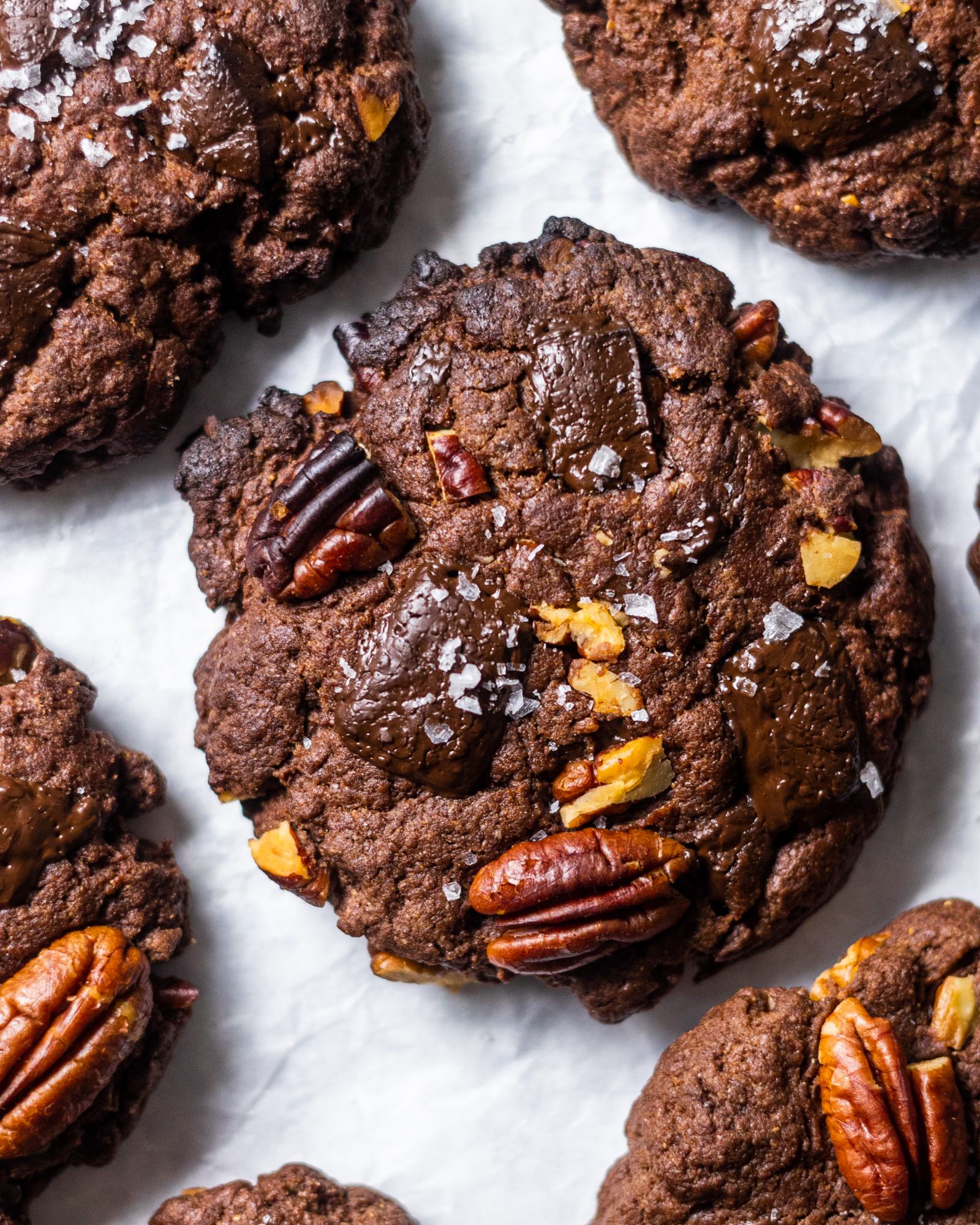 Vegan double Chocolate chip Cookies with pecans. photographed from above, arranged on white baking parchment