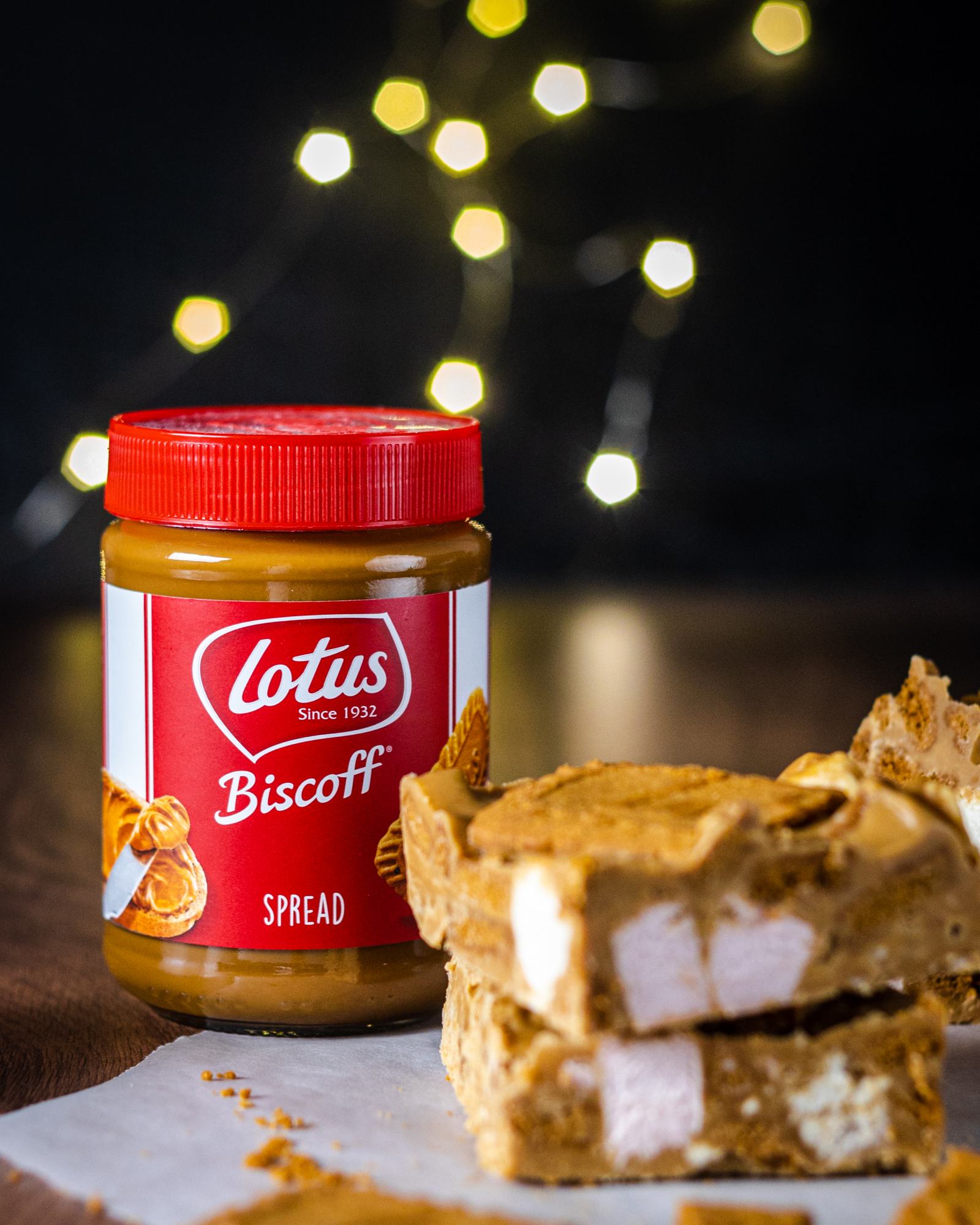a jar of biscoff spread next to biscoff rocky road on a dark wooden table