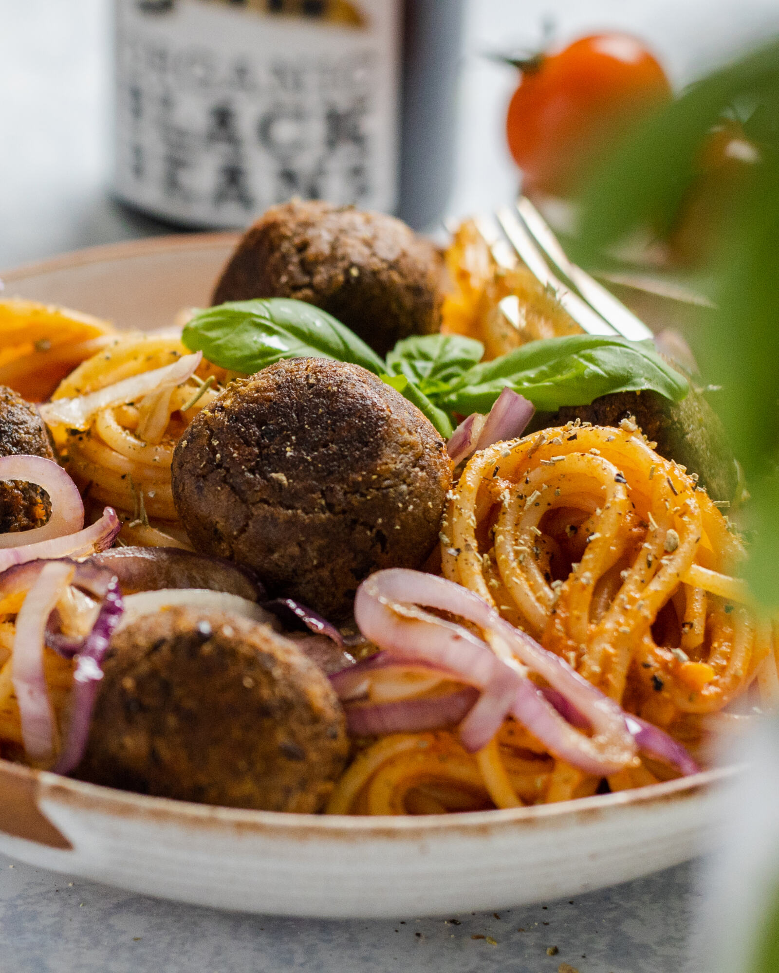 vegan black bean meatballs up close with spaghetti in a bowl