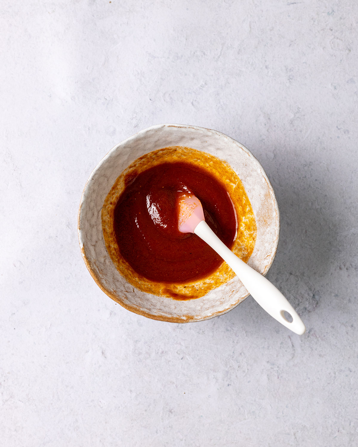 vegan bbq sauce in a whilte bowl with a small spatula