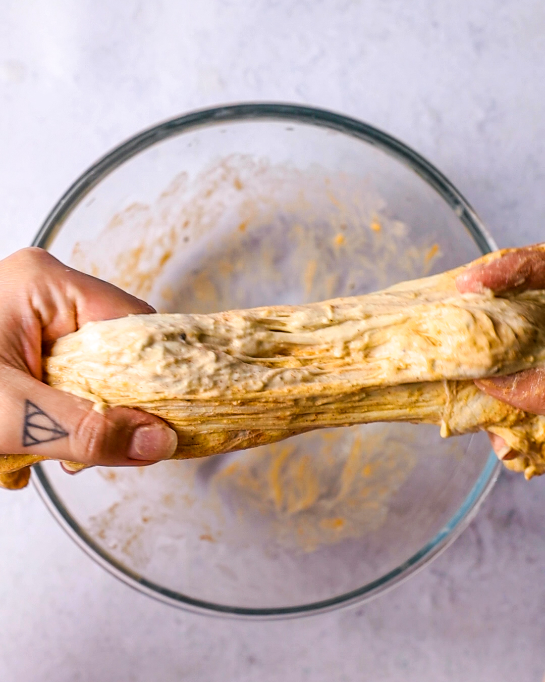 hands stretching and kneading a washed flour dough ball