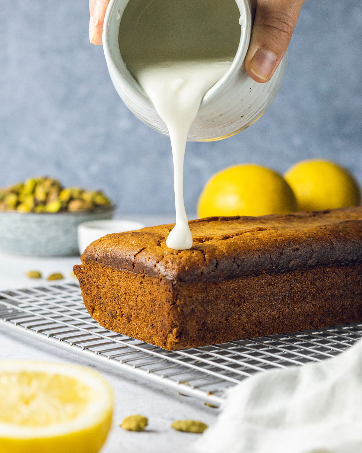 Lemon glaze been put onto a pistachio loaf cake