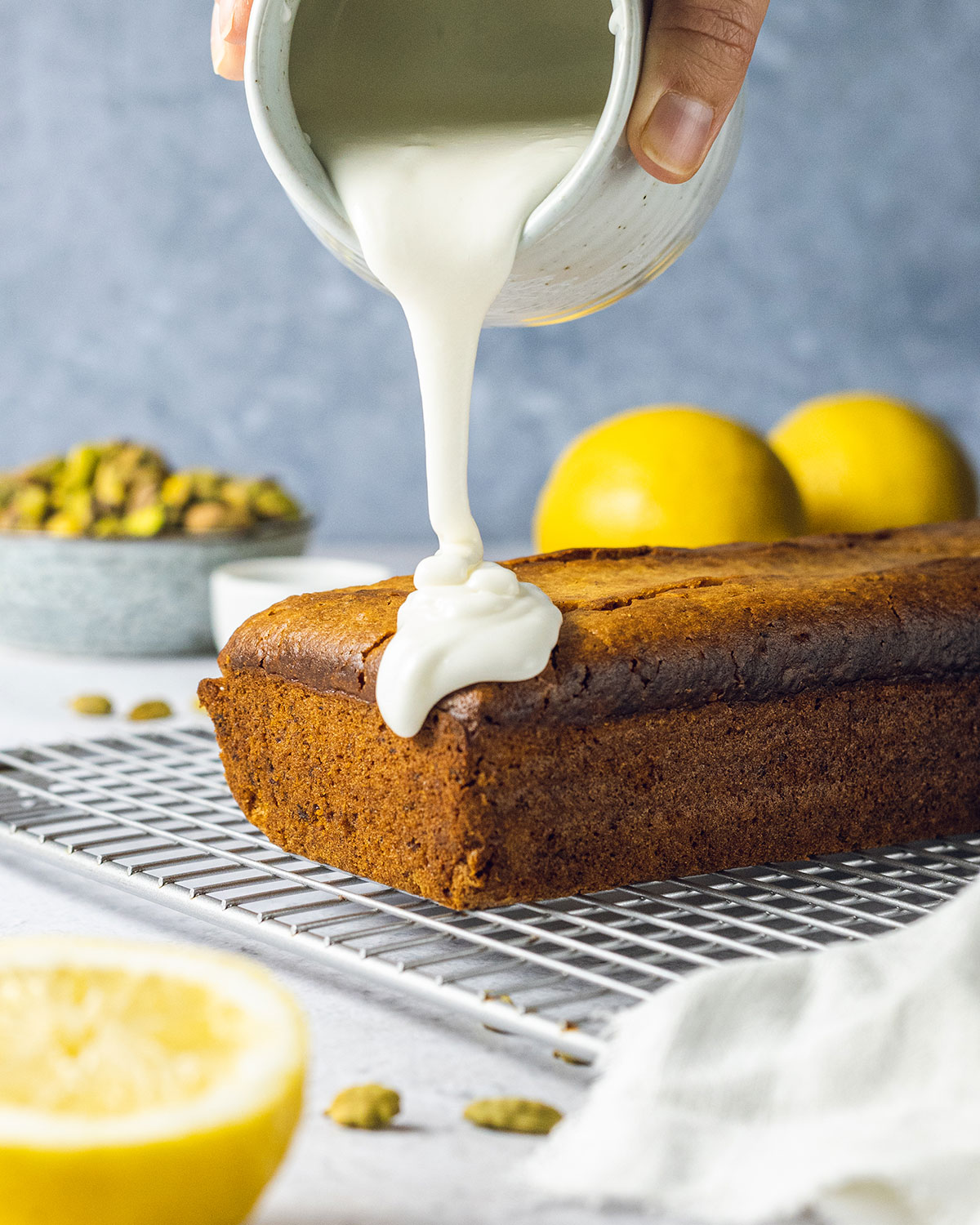 Lemon glaze been put onto a pistachio loaf cake