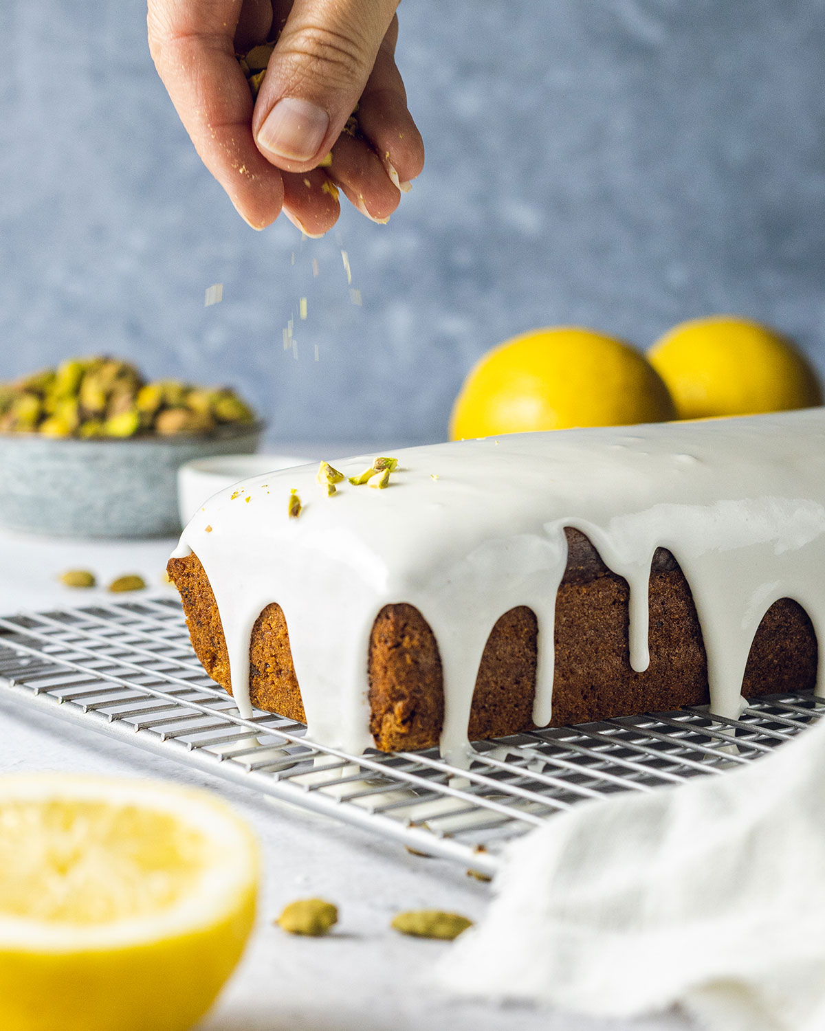 Hands sprinkling pistachio nuts on the cake place