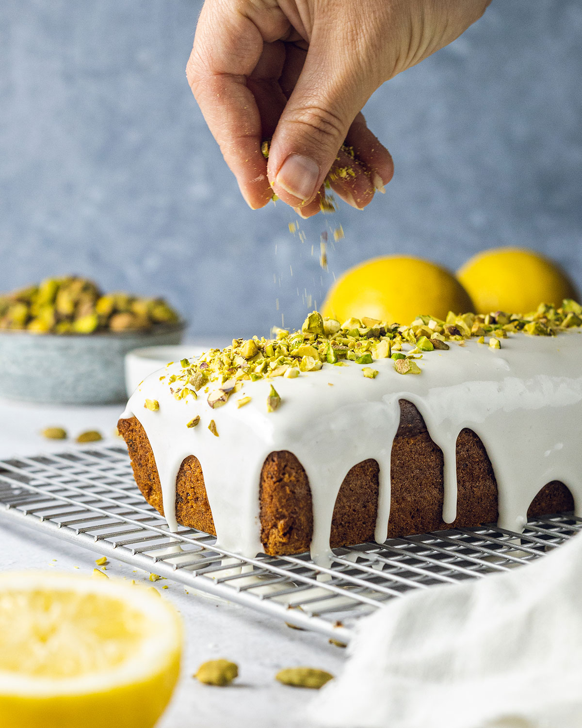 Sprinkling crushed pistachios onto a lemon and cardamom pistachio loaf cake