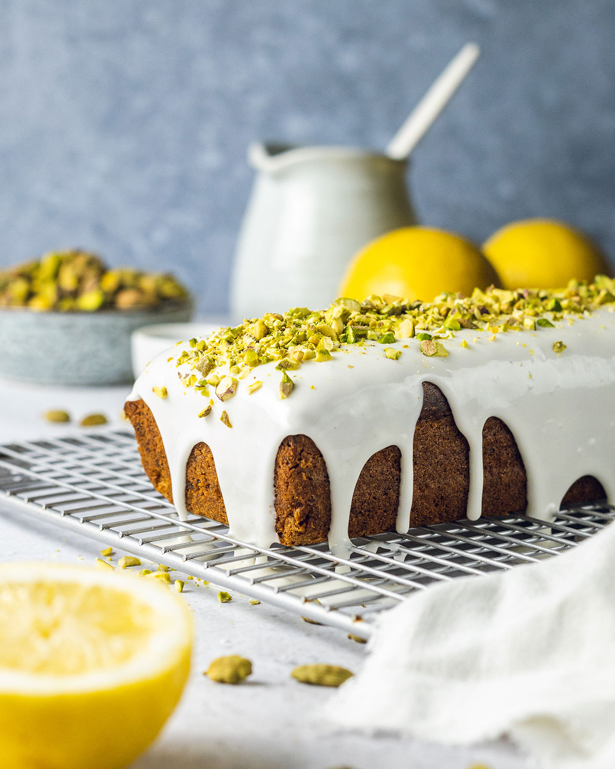 Vegan pistachio cake loaf topped with lemon glaze and pistachio nuts