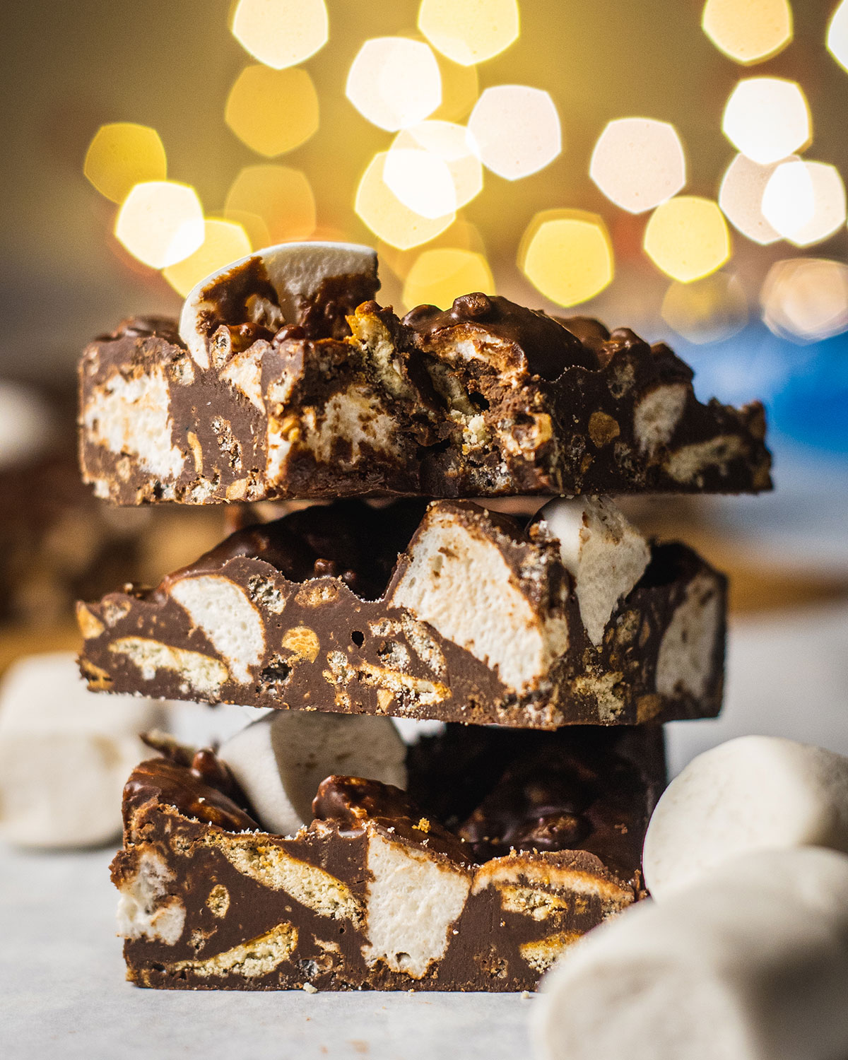 a stack of 3 slices vegan rocky road with a bite taken out of the slice on top