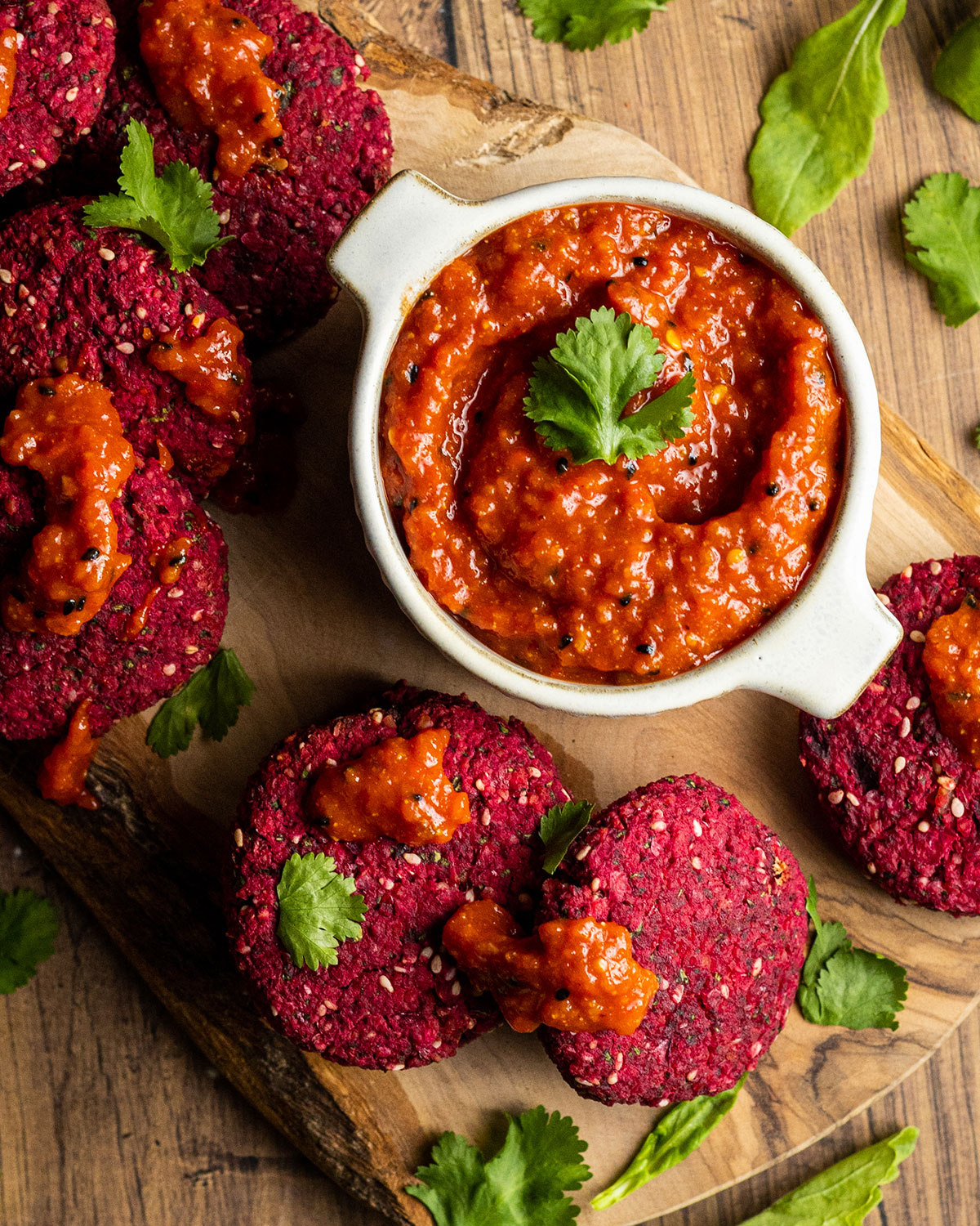 homemade harissa paste in a bowl surrounded by beetroot falafel