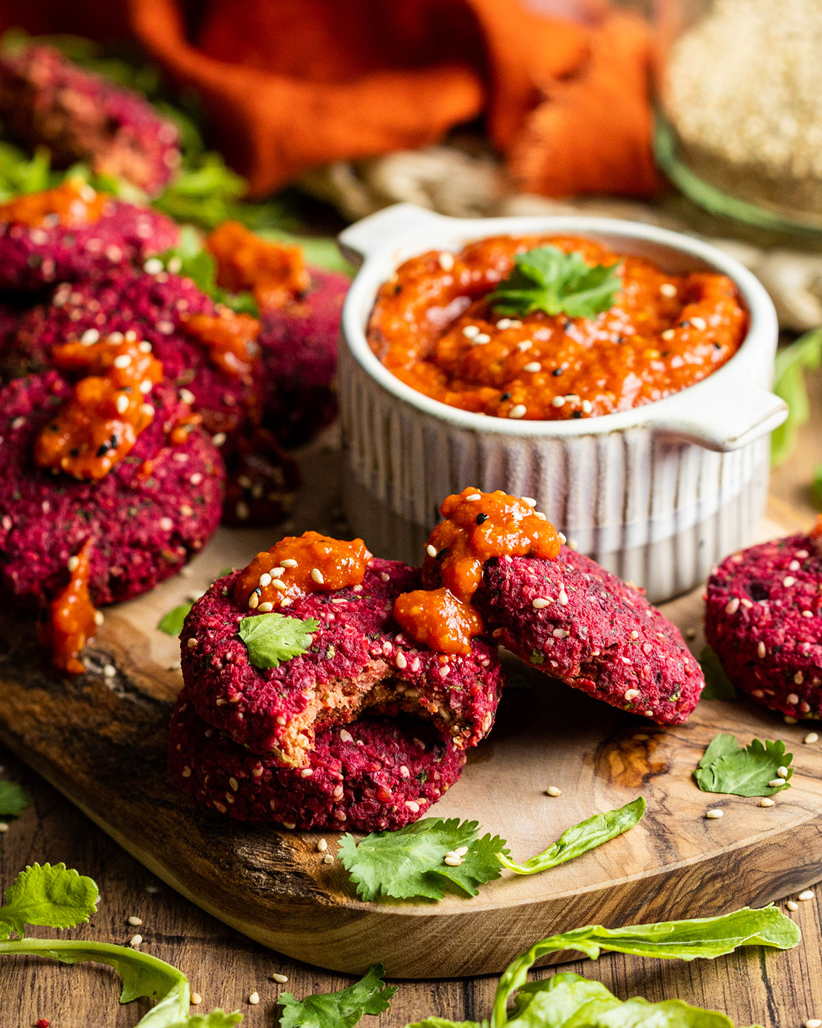 beetroot falafels on a wooden board with a pot of harissa paste on the side