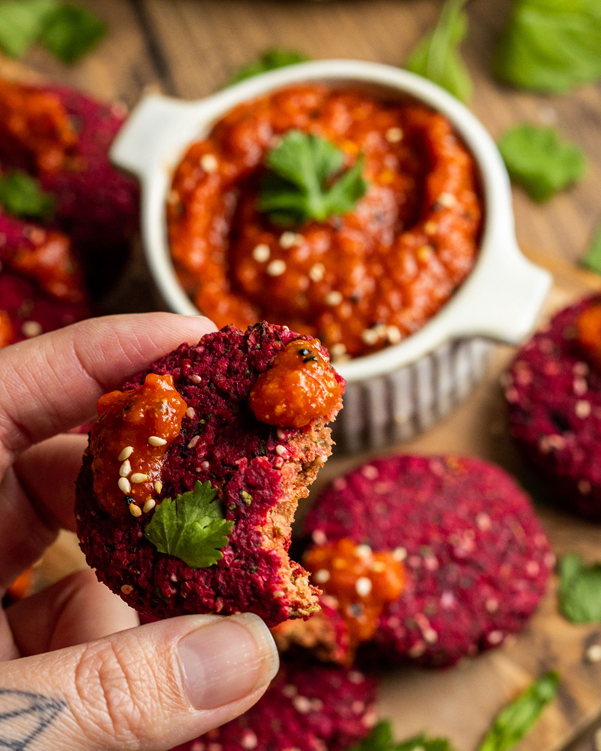 a hand holding a beetroot falafel