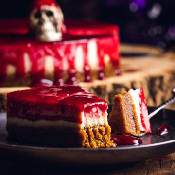 a slice of halloween cheesecake on a black plate with a bite taken out of it