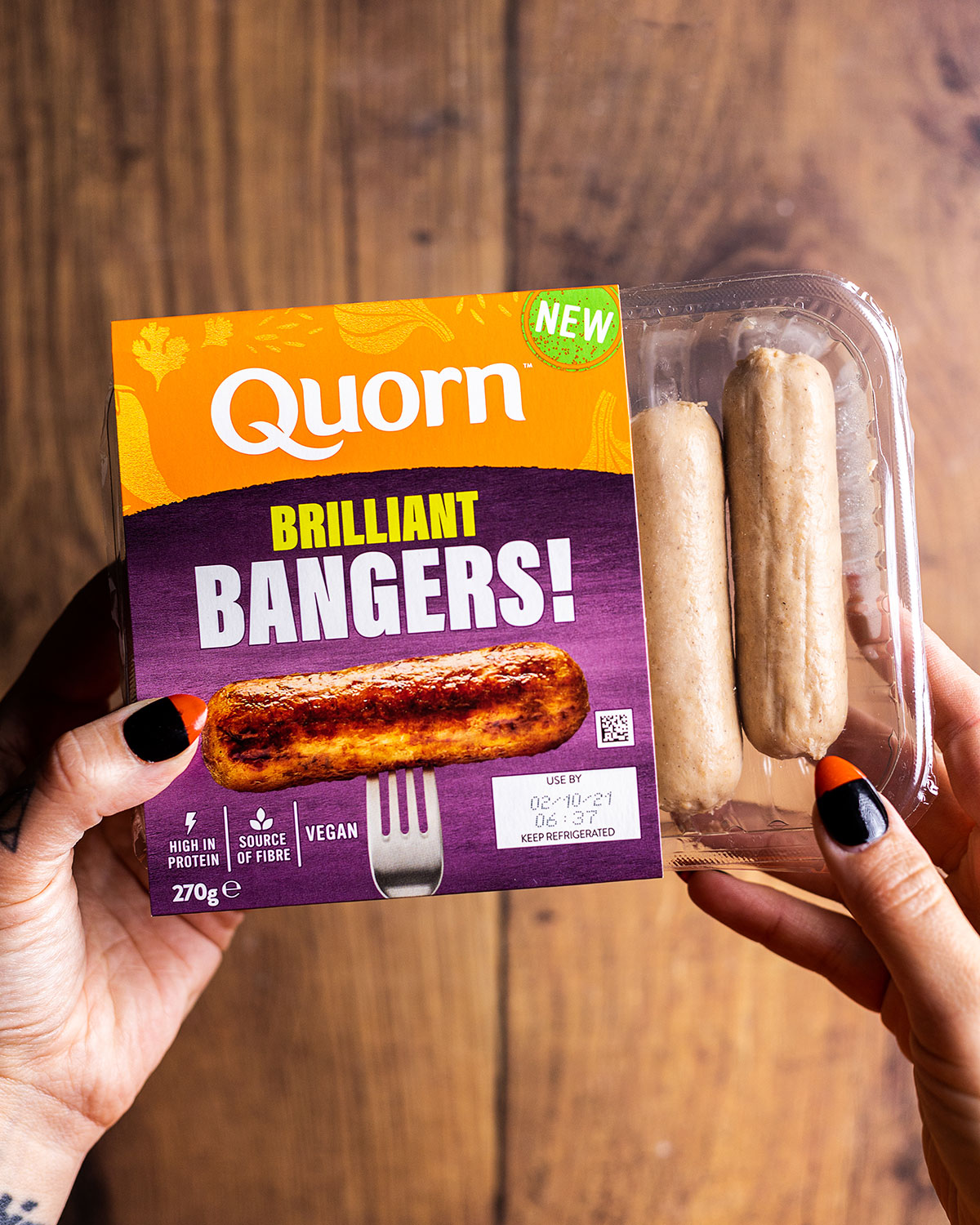 a hand holding a pack of Quorn Brilliant Bangers