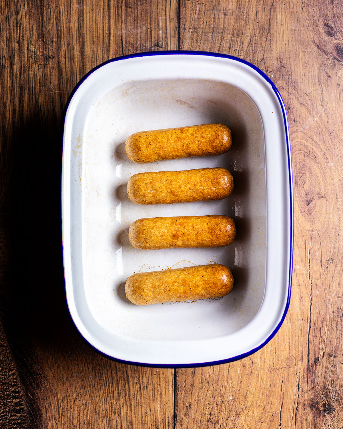 four cooked sausages in an oven dish