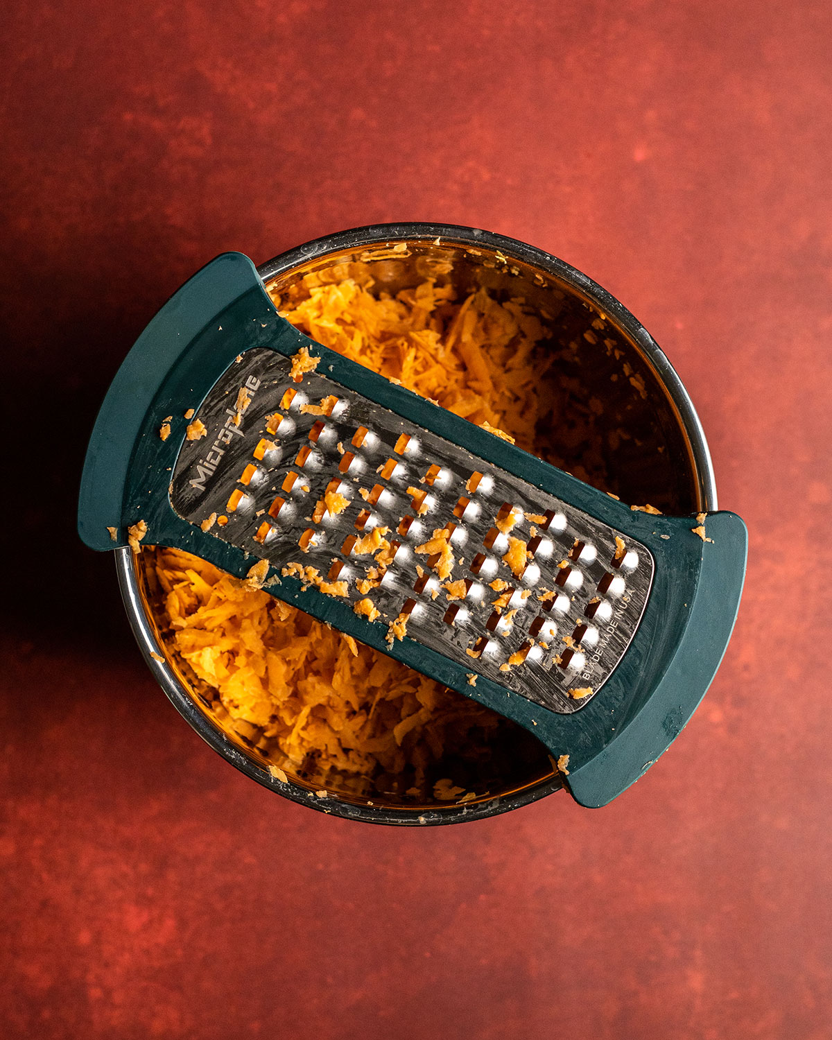 the bowl filled with sweet potato shreds and the bowl grater sitting on top