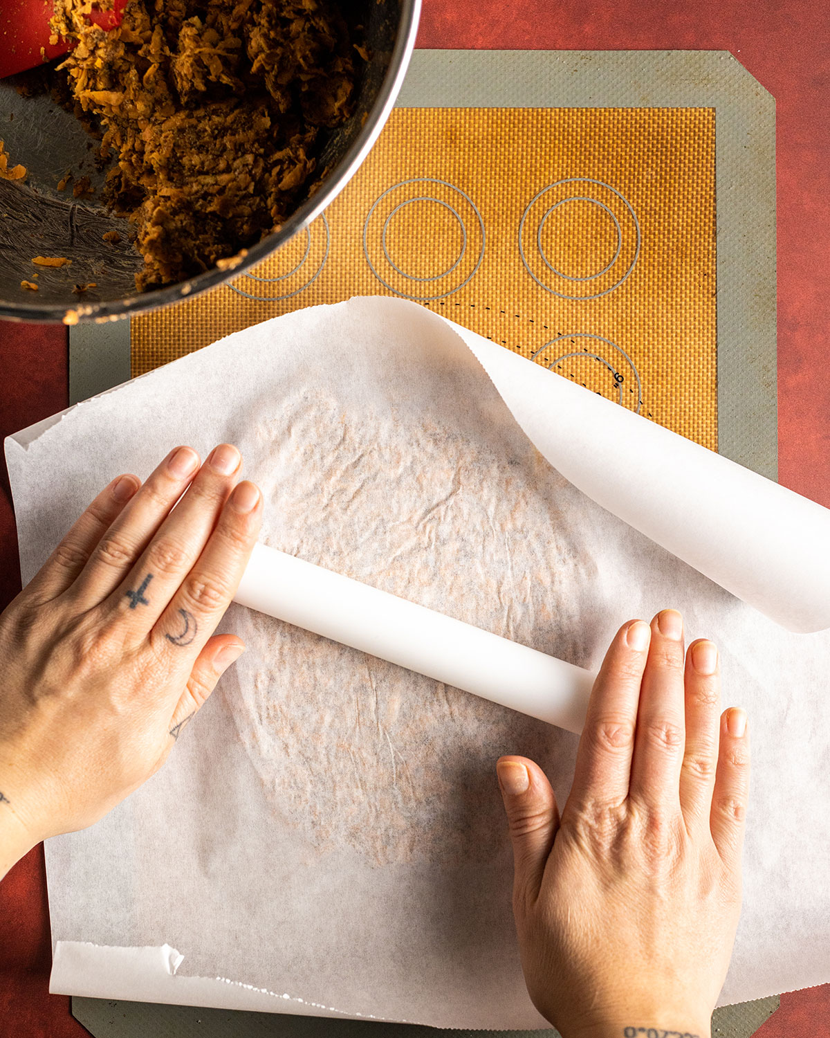 rolling the dough flat with a parchment paper on top of the cracker dough