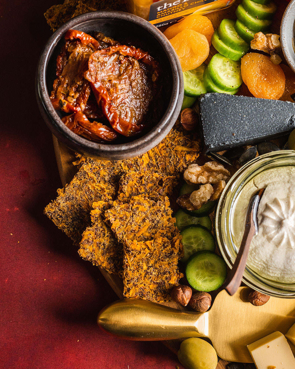 A close up of a vegan cheeseboard corner with homemade sweet potato crackers piled up on the edge.