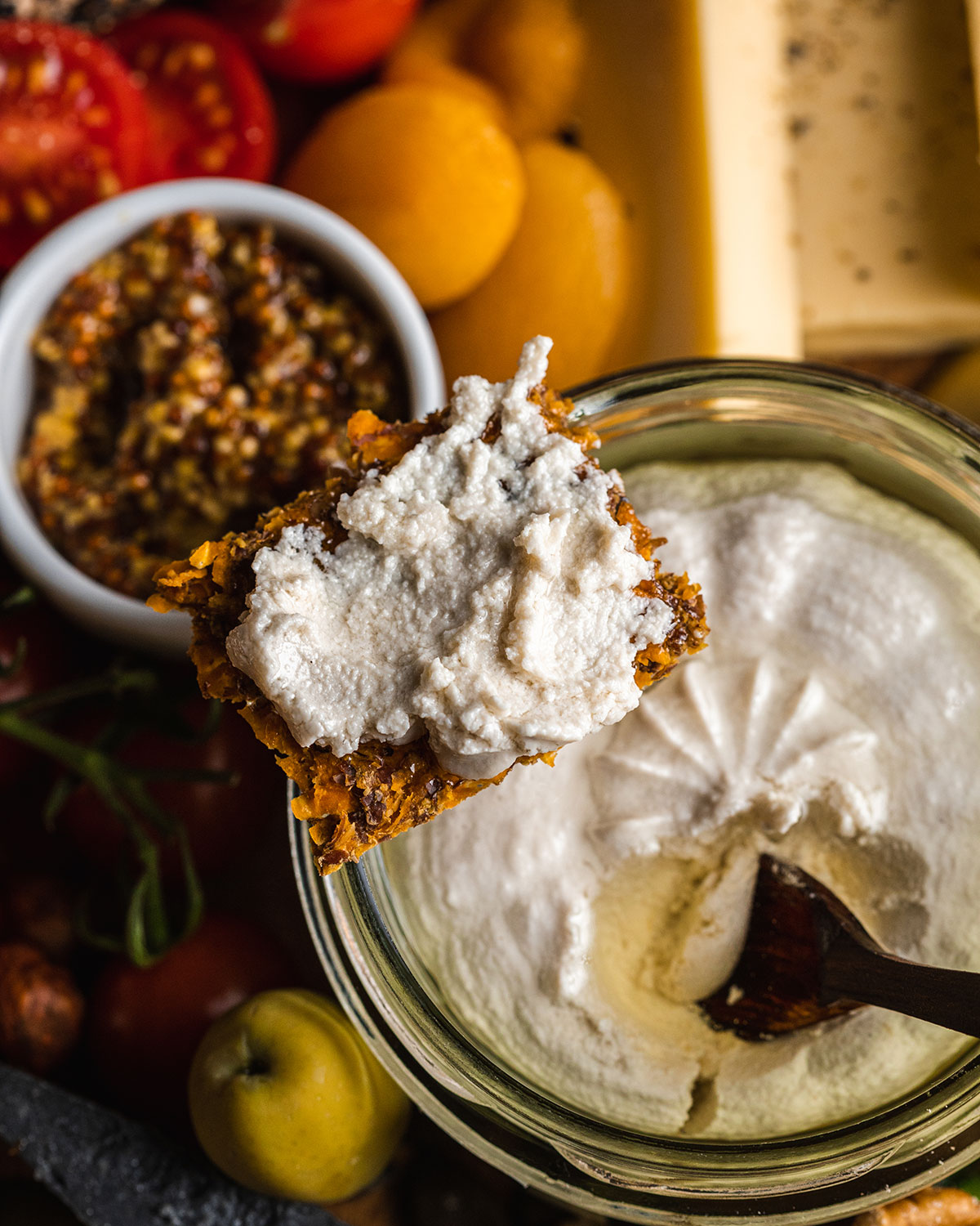 cracker with vegan ricotta sitting on the edge of the vegan ricotta jar