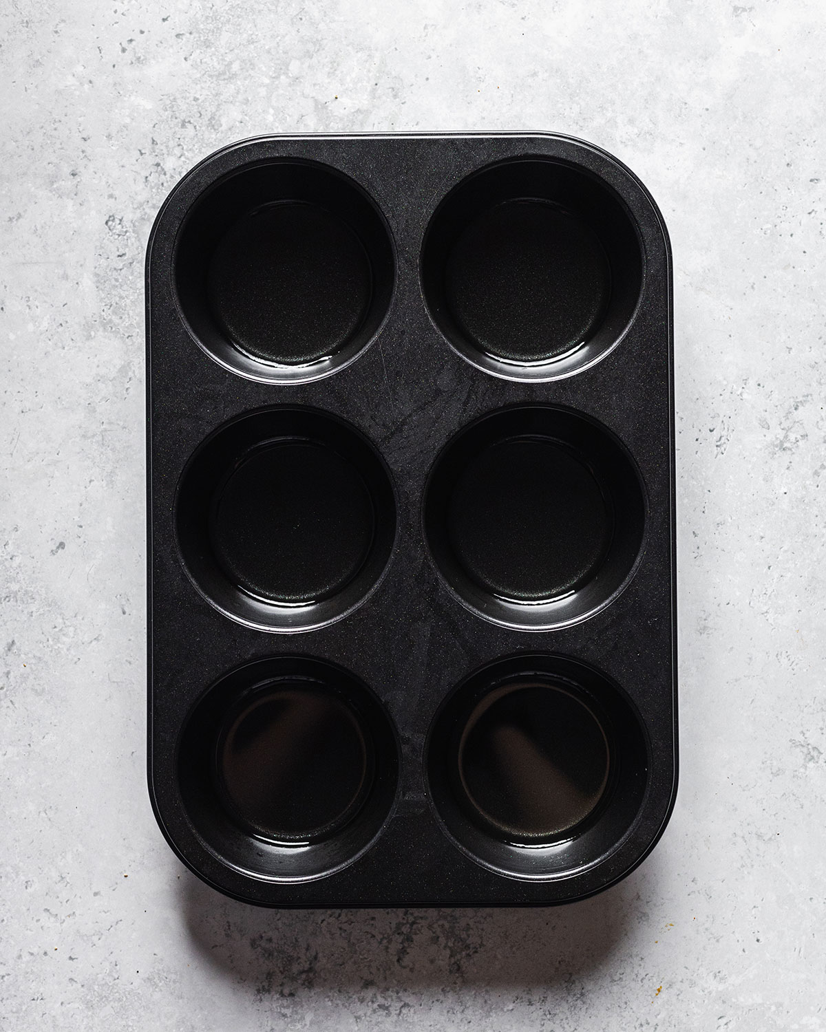 A large six whole muffin tray filled with oil for creating vegan Yorkshire puddings