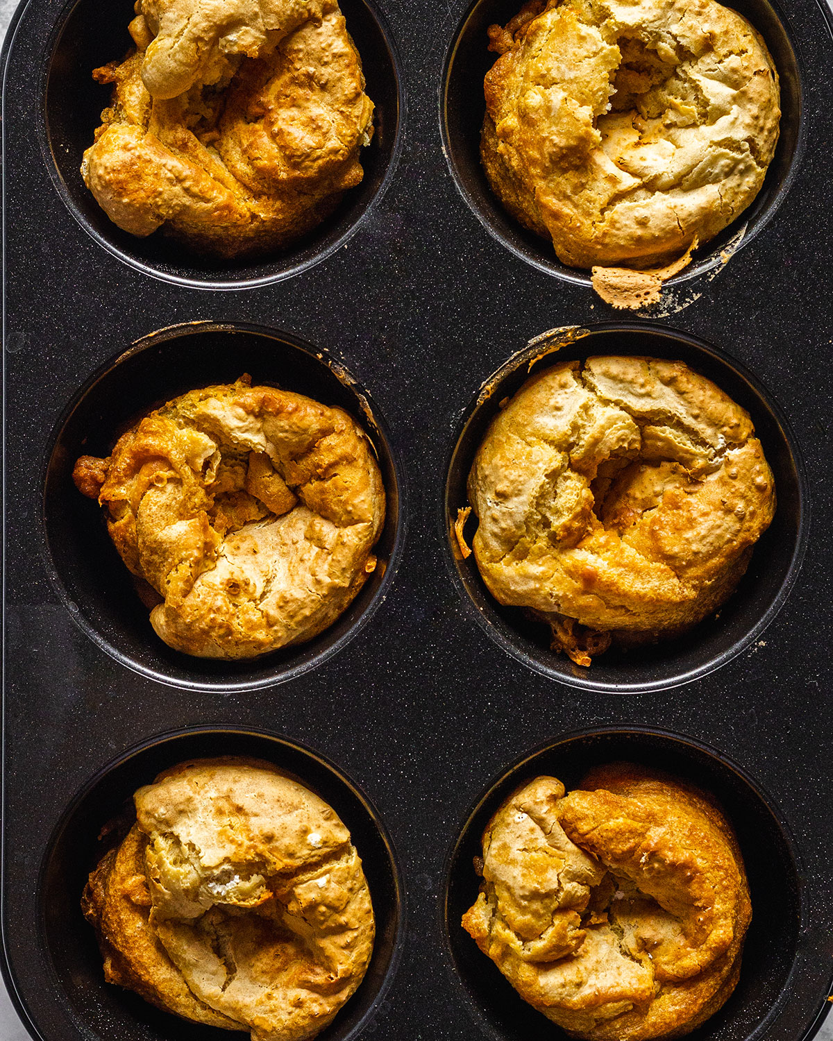 Close-up of a six hole muffin tray filled with vegan Yorkshire puddings