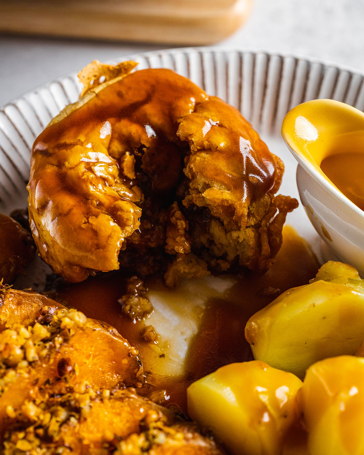 A close-up photograph of a Yorkshire pudding on a plate filled with a vegan roast