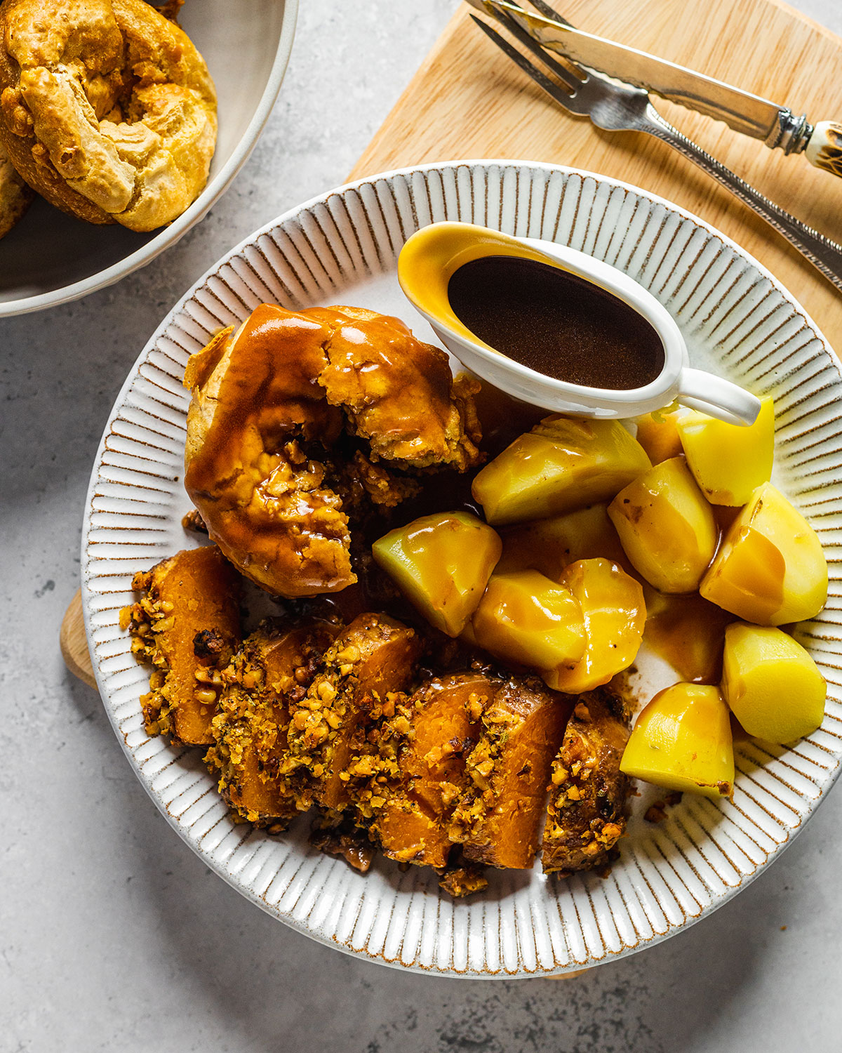 A delicious vegan roast dinner on a white plate including the vegan Yorkshire pudding covered in vegan gravy