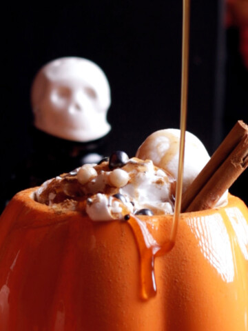 Vegan Pumpkin Spice syrup is drizzled on a drink in pumpkin mug.