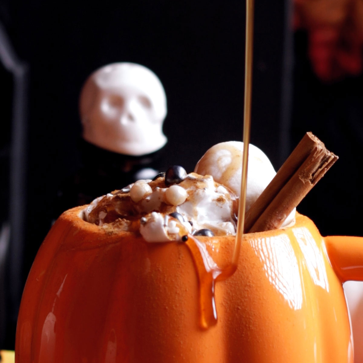 Vegan Pumpkin Spice syrup is drizzled on a drink in pumpkin mug.