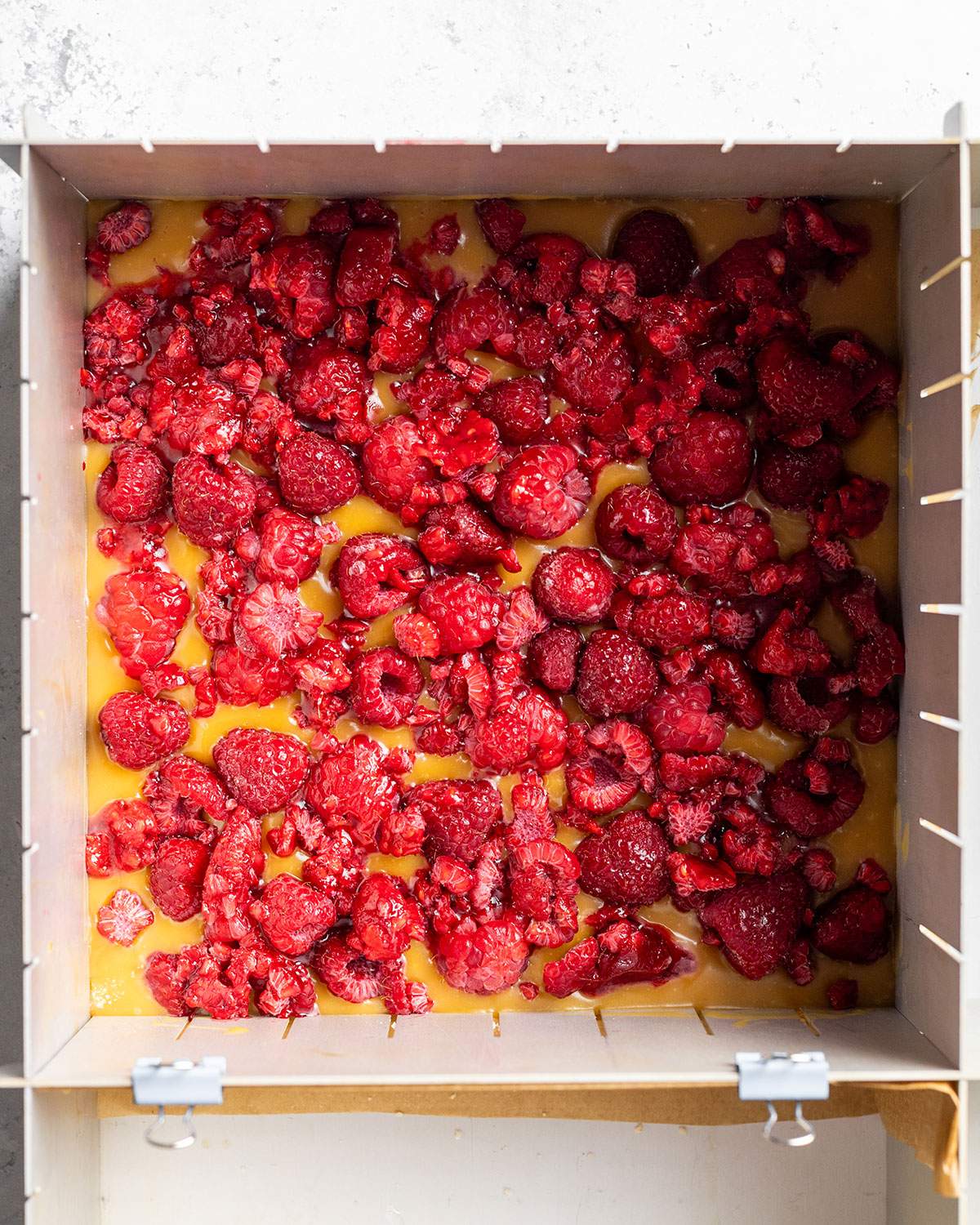 Fresh raspberries have been added on top of the butterscotch and are almost covering up the sauce underneath.