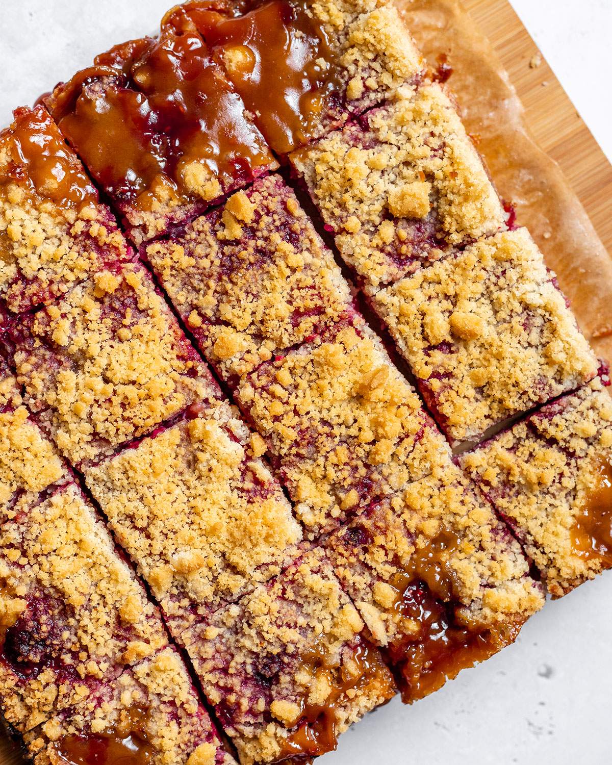 Sliced crumble bars are sitting on a cutting board and shown from the top with the cut lines clearly visible.