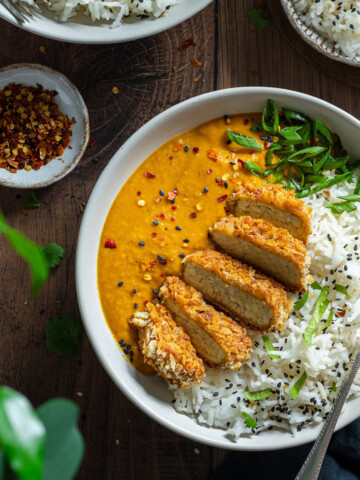 Vegan Katsu Curry with Tempeh - two bowls on a dark wooden table top, with a fork in each bowl