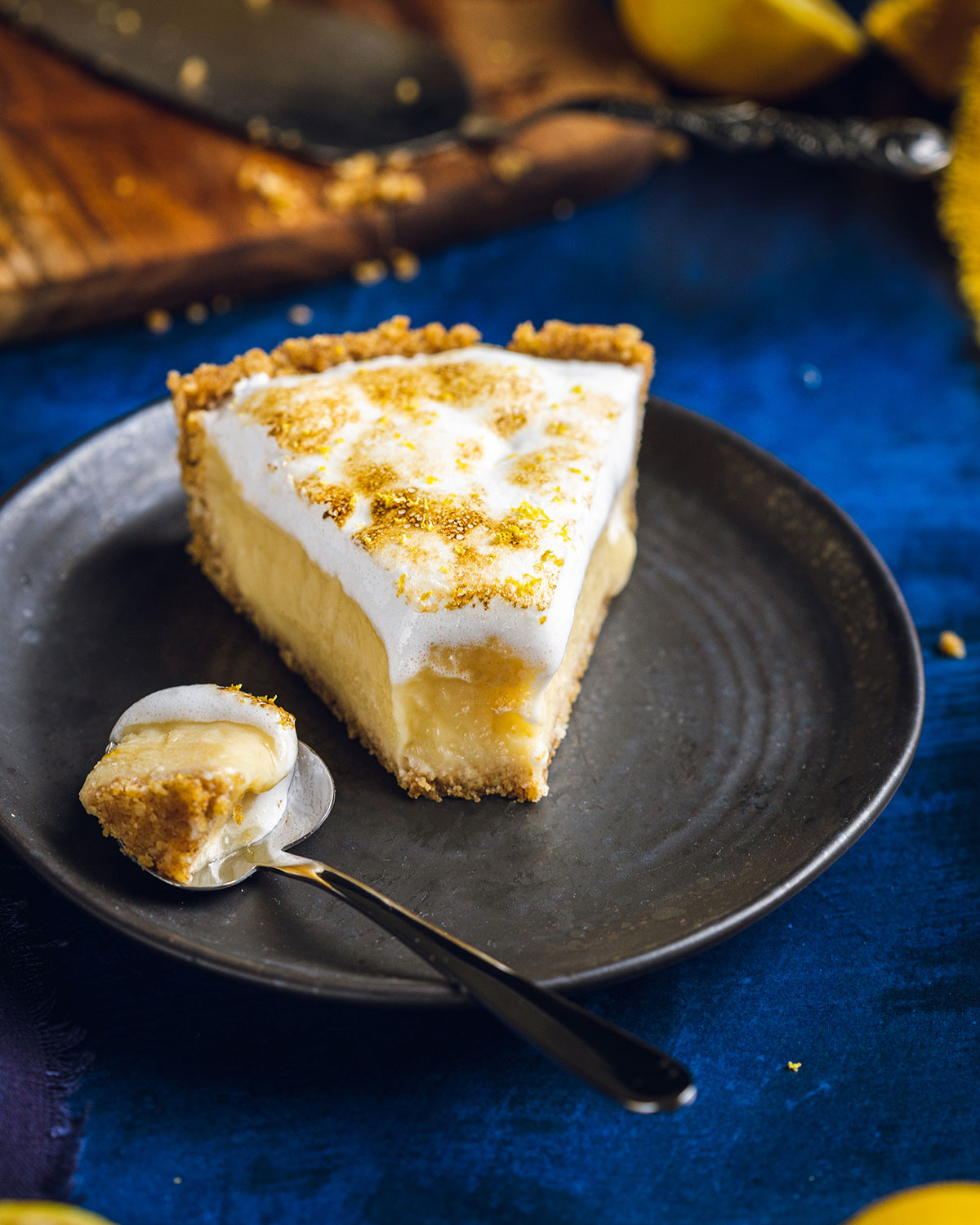 a slice of vegan lemon meringue pie on a black plate