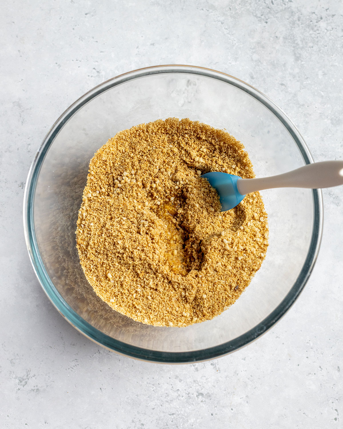 a bowl filled with crumbles biscuits and melted butter added to it