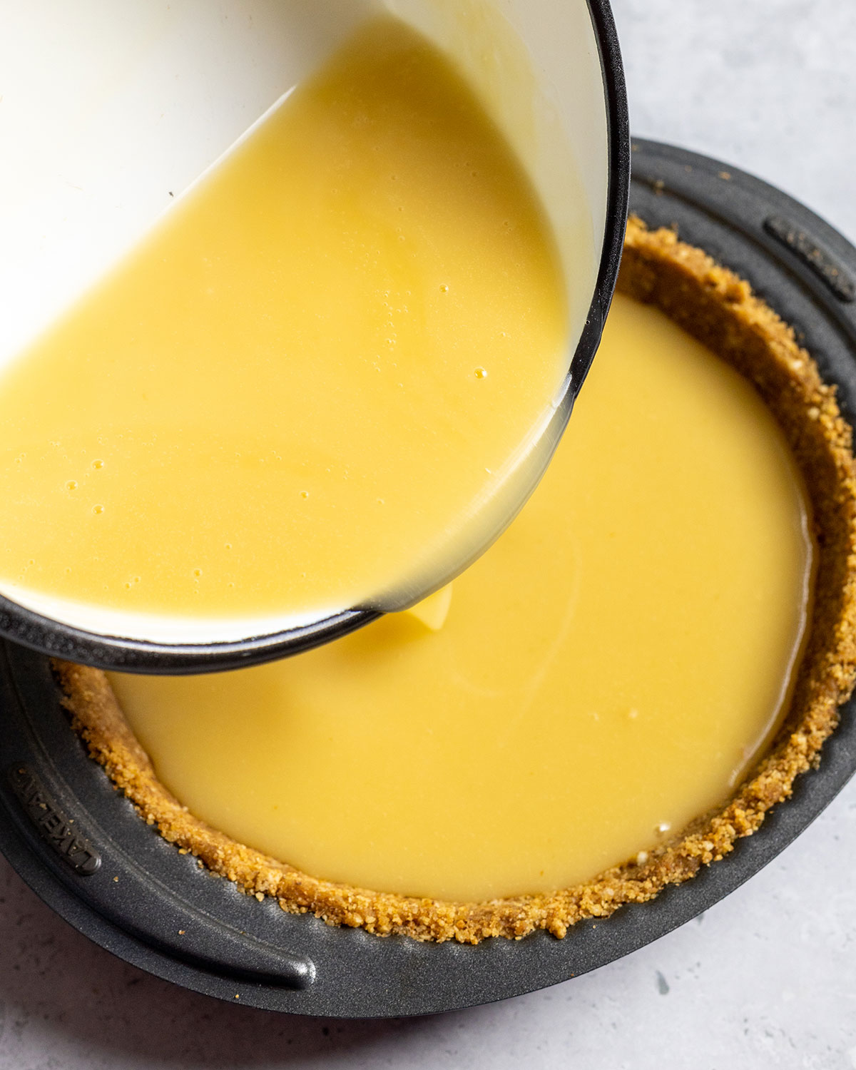 vegan lemon curd being poured into a pie base