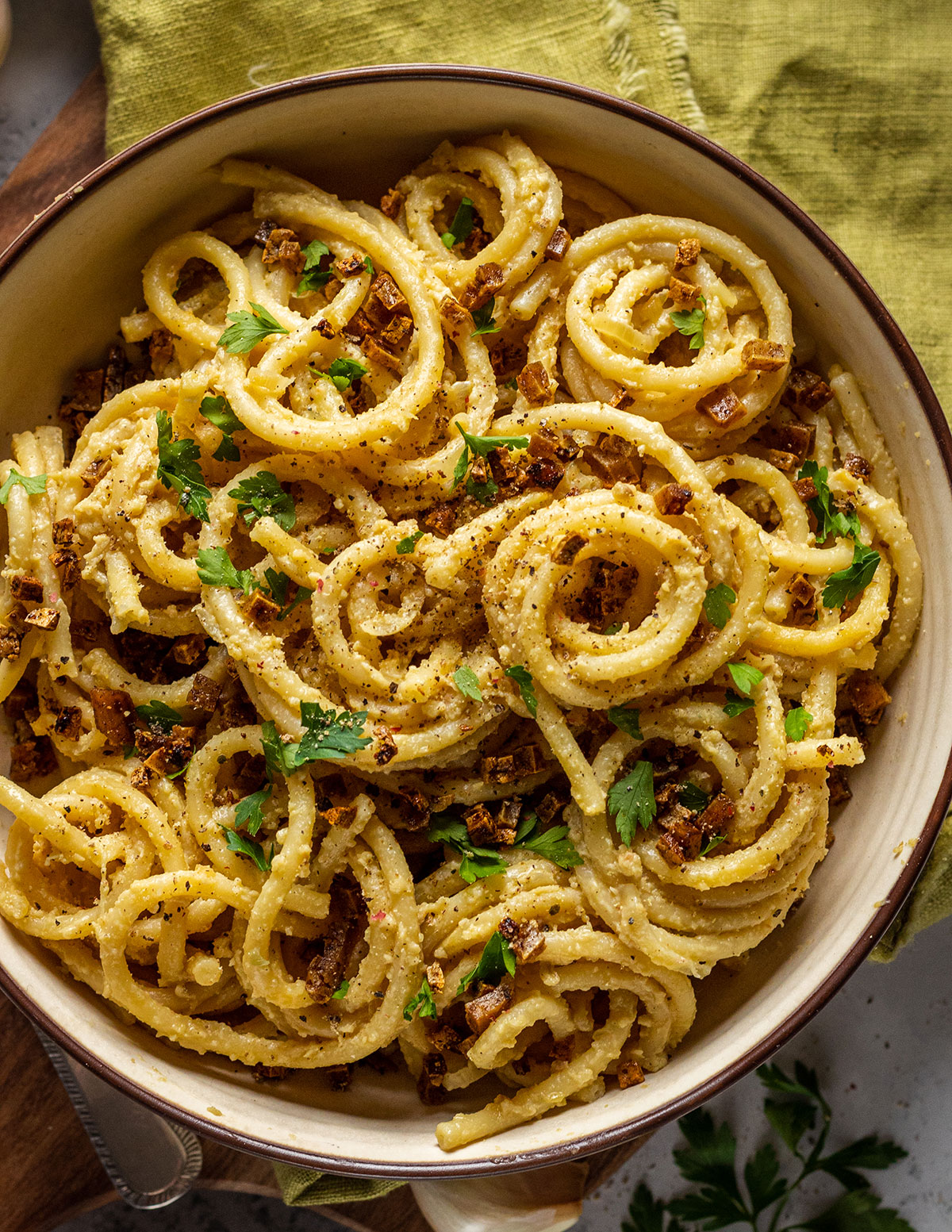 A bowl filled with vegan carbonara spaghetti and smoked tofu bacon pieces