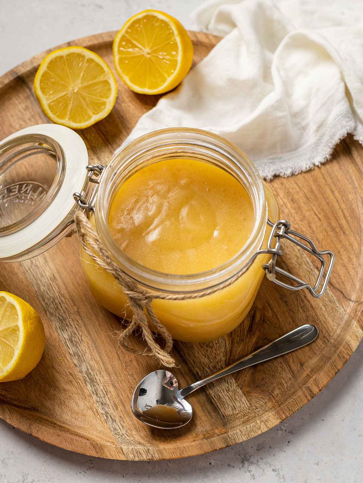 vegan lemon curd in a glass jar on a wooden plate