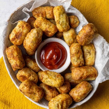 air fryer tater tots in a serving bowl alongside ketchup
