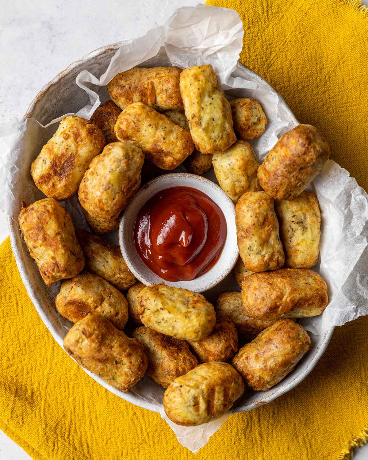 air fryer tater tots in a serving bowl alongside ketchup