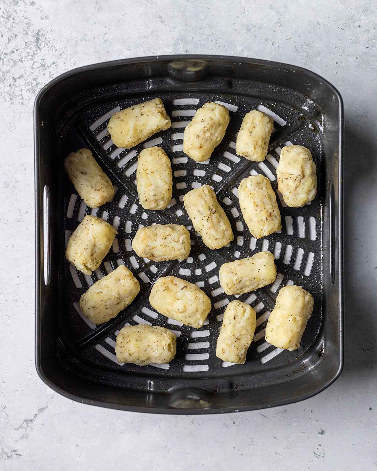 uncooked tater tots in an air fryer basket