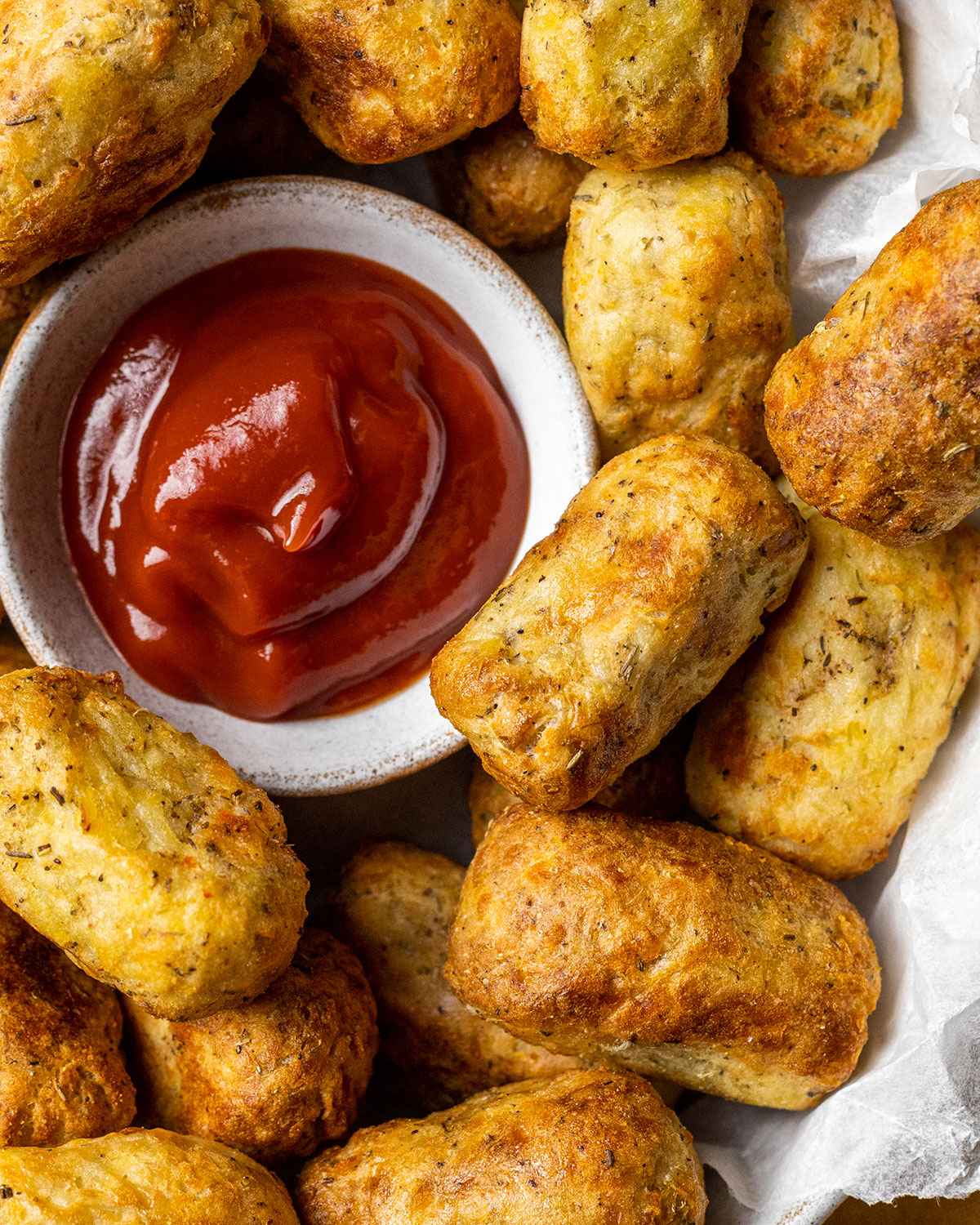 close up of air fried tater tots next to a serving of ketchup