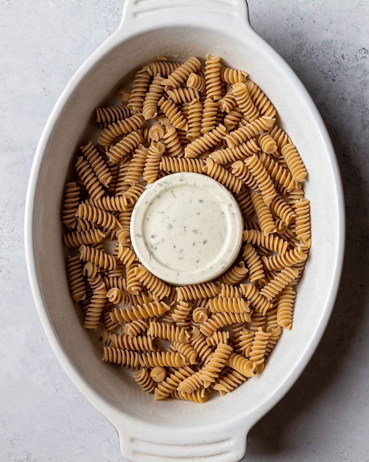 fusilli pasta surrounding the boursin cheese in the baking dish