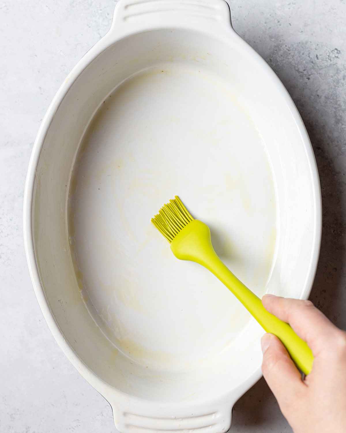 greasing the oven dish with olive oil using a brush
