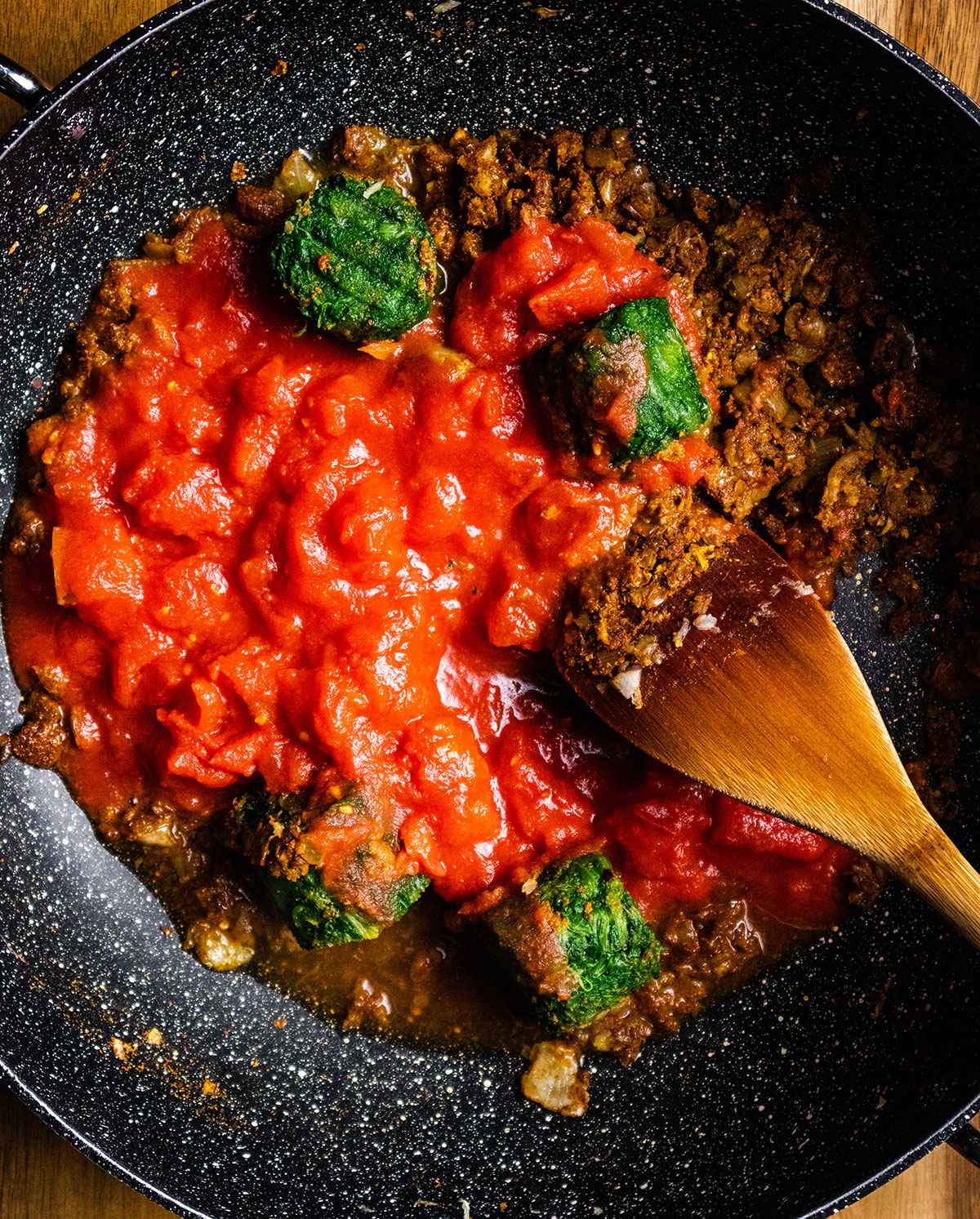 Tomatoes and spinach are added to the skillet.