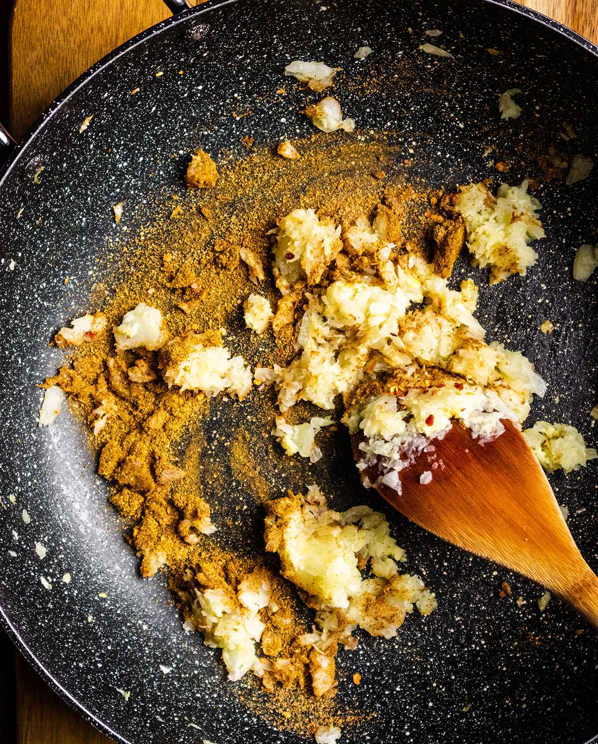 Aromatics and spices for the bean curry are becoming fragrant in a large skillet.