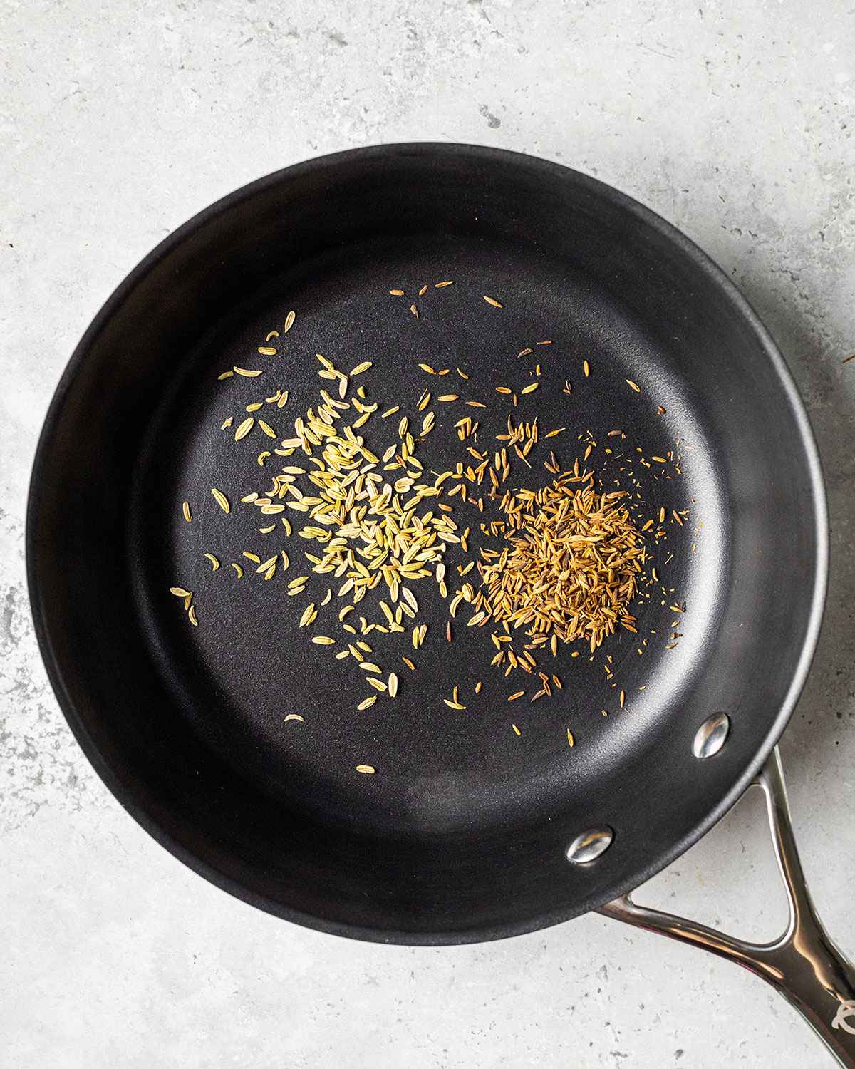 fennel seeds and cumin seeds in an Olav frying pan toasting