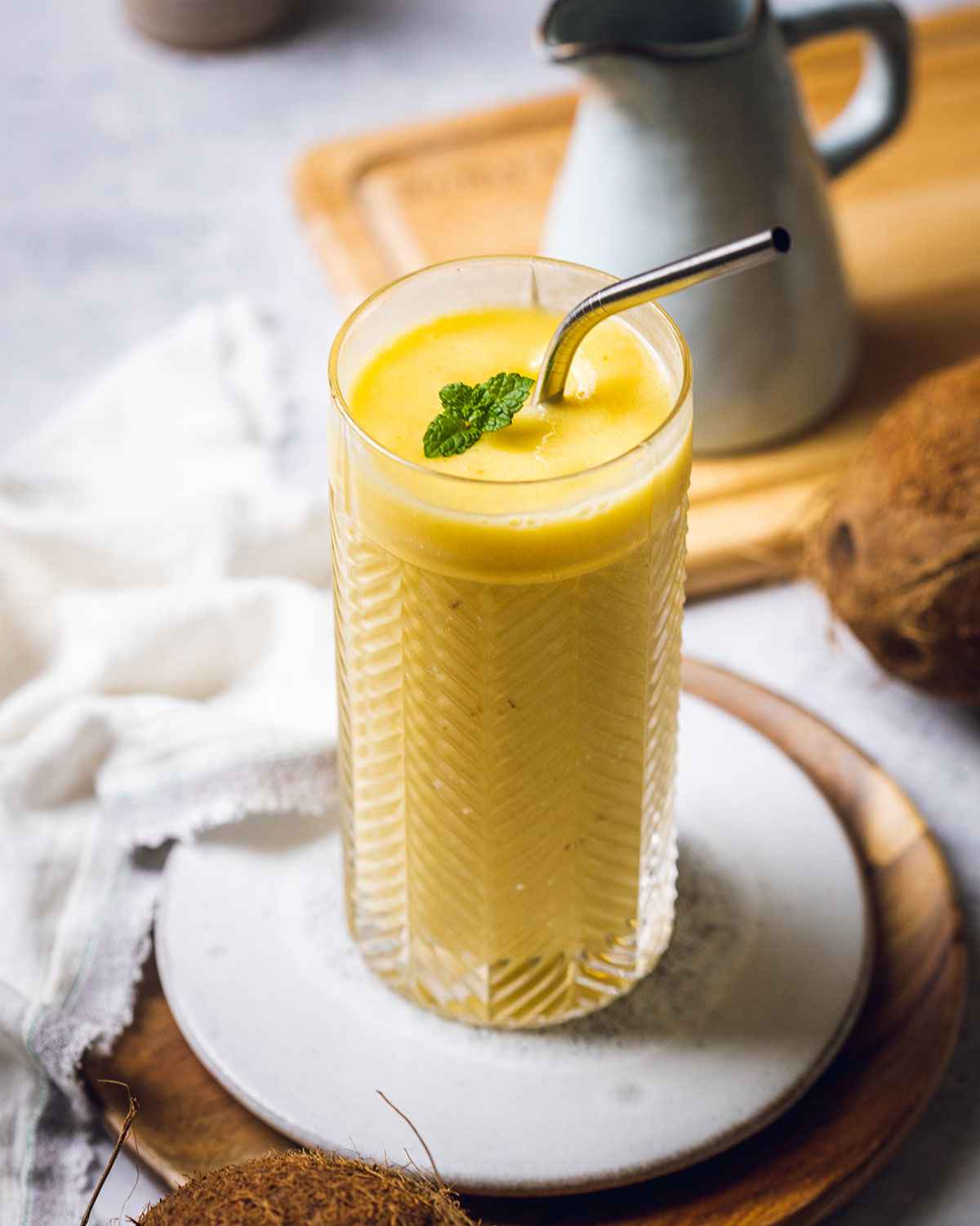 mango pineapple smoothie in a tall glass topped with fresh mint