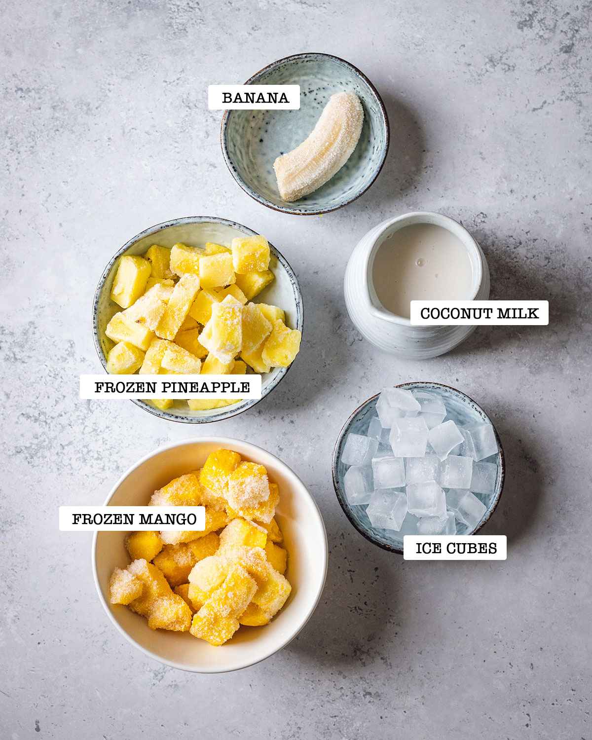 ingredients for pineapple mango smoothie on a white marble table