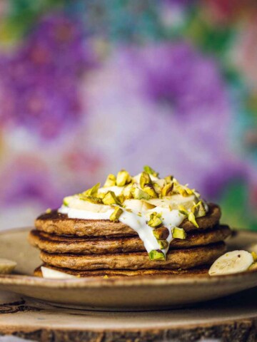 stacked vegan banana pancakes topped with dairy free yogurt and banana
