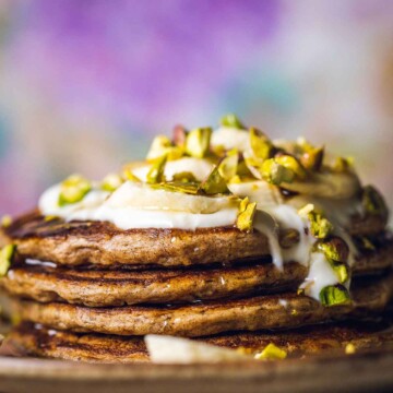 stacked banana pancakes in front of a purple background