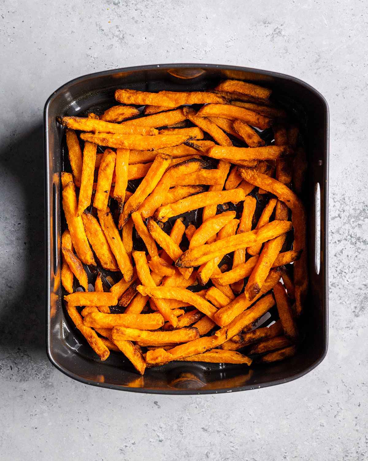 cooked sweet potato fries in an air fryer basket